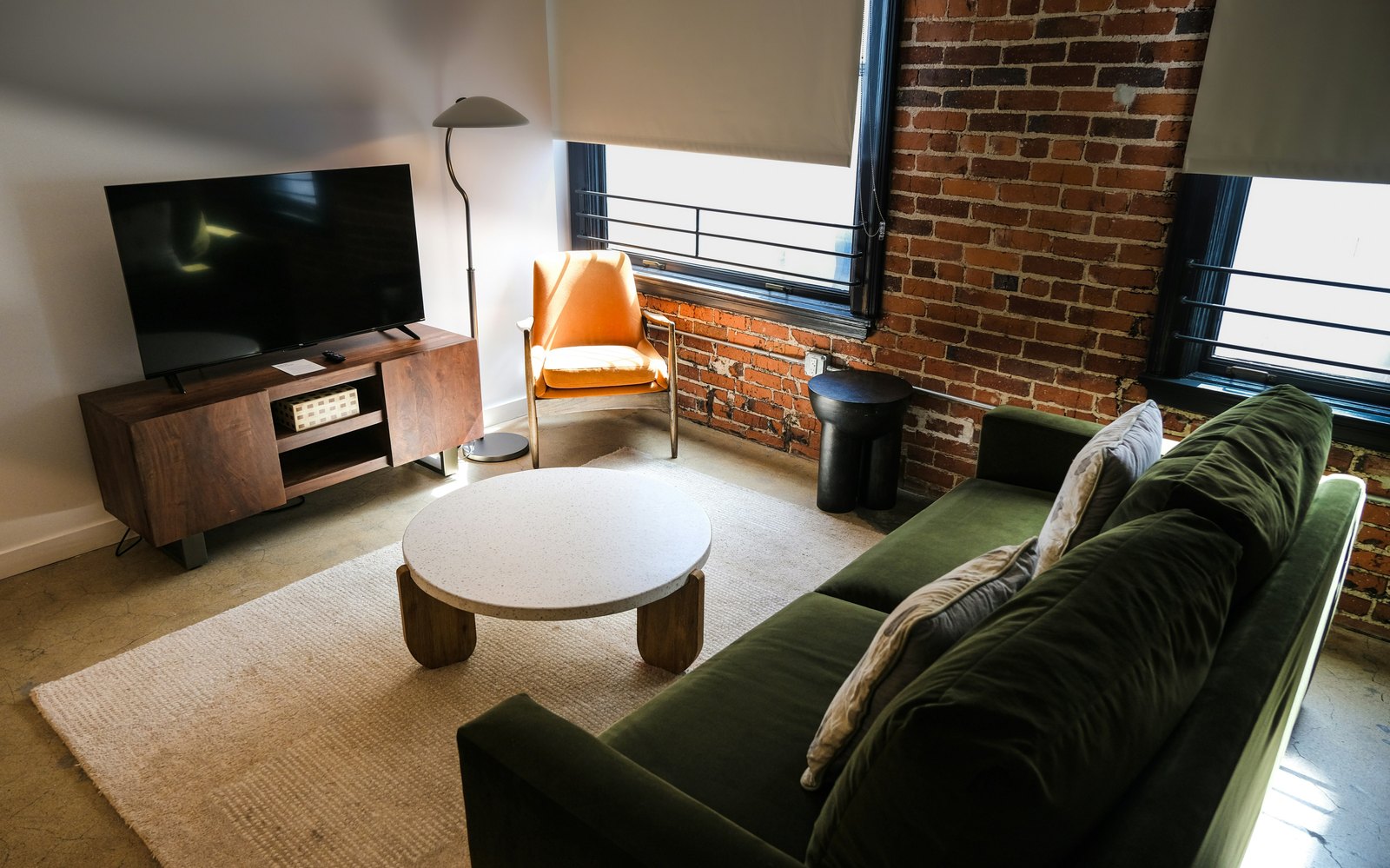 A living room with a brick wall and an industrial window