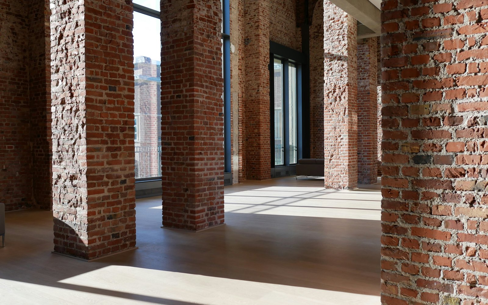 An empty loft floor with brick columns and tall windows
